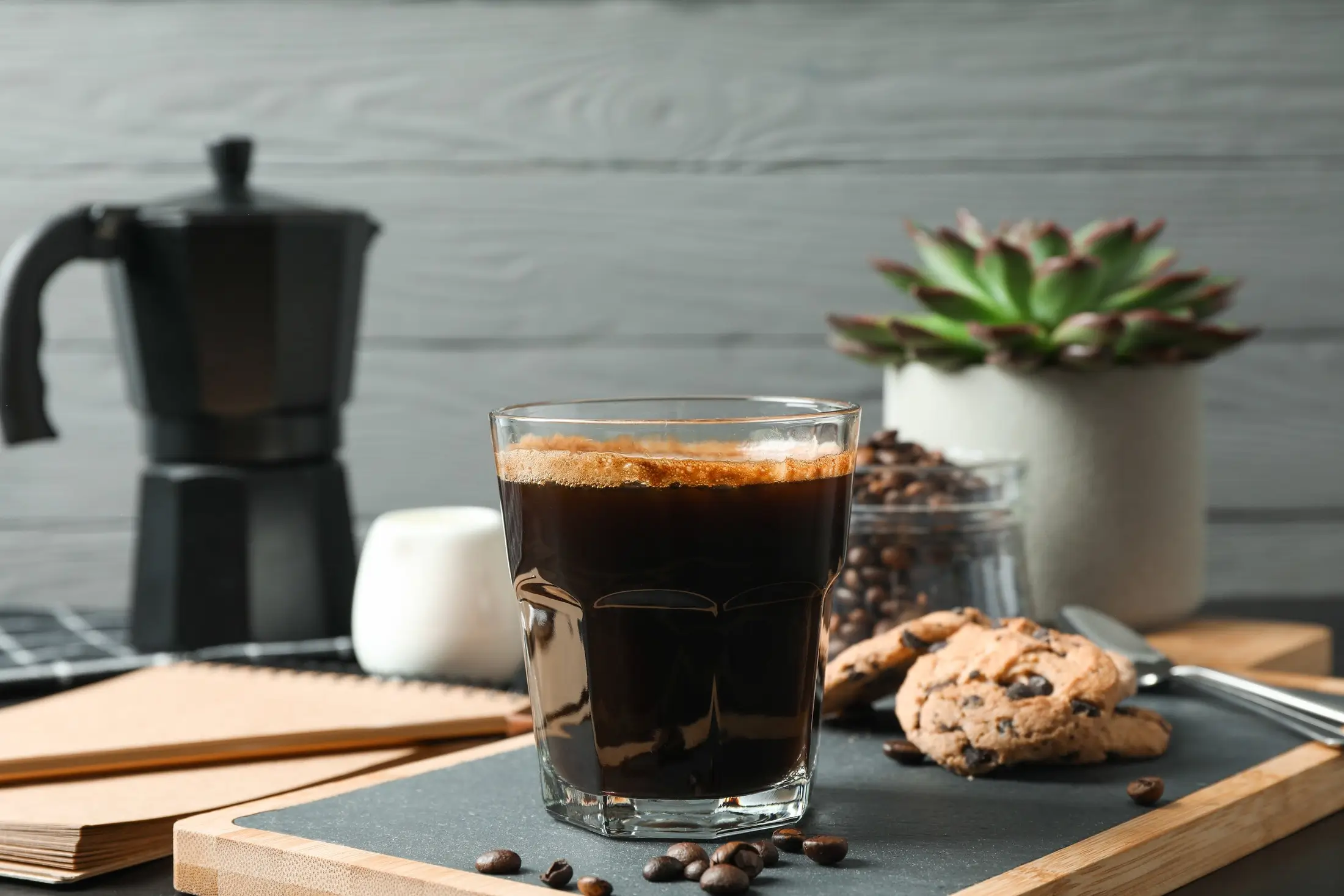 Freshly brewed espresso with coffee beans and a cookie