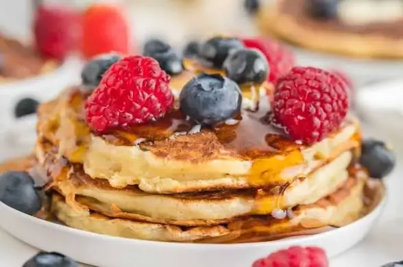 Pancakes topped with berries and maple syrup
